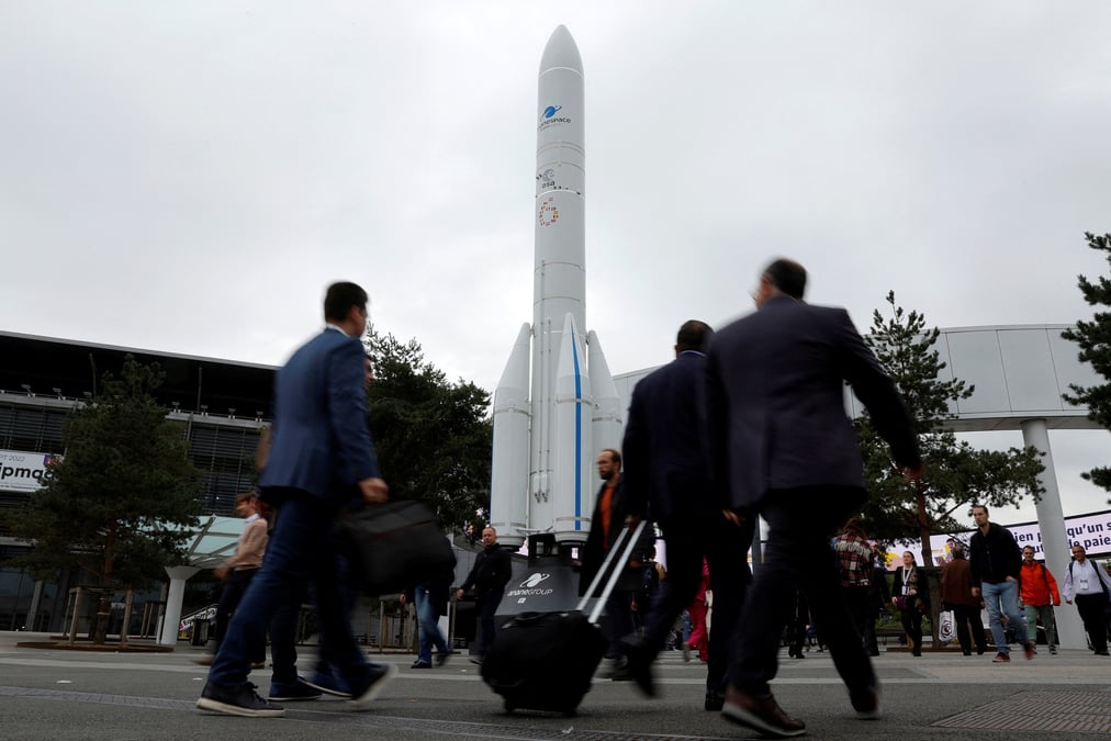 Des visiteurs passent devant la maquette d'une fusee a l'entree du congres international d'astronautique (iac) a paris