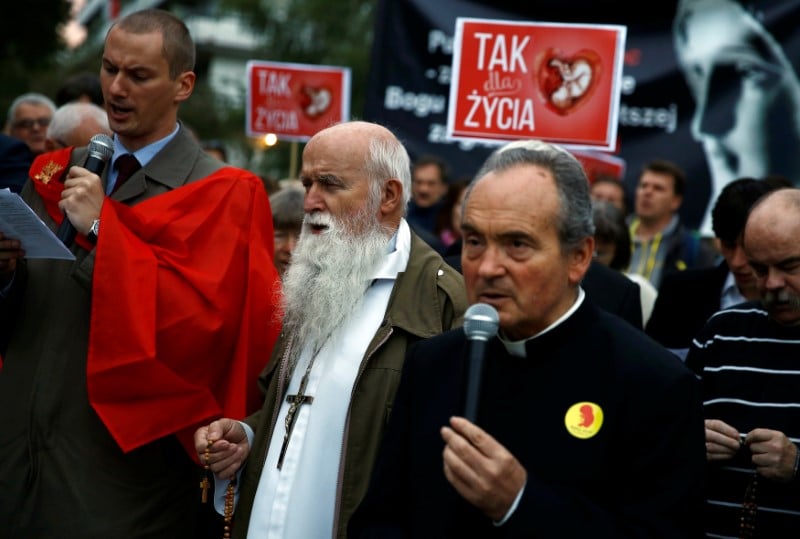 People pray as they take part in an anti-abortion demonstration in front of the parliament in warsaw