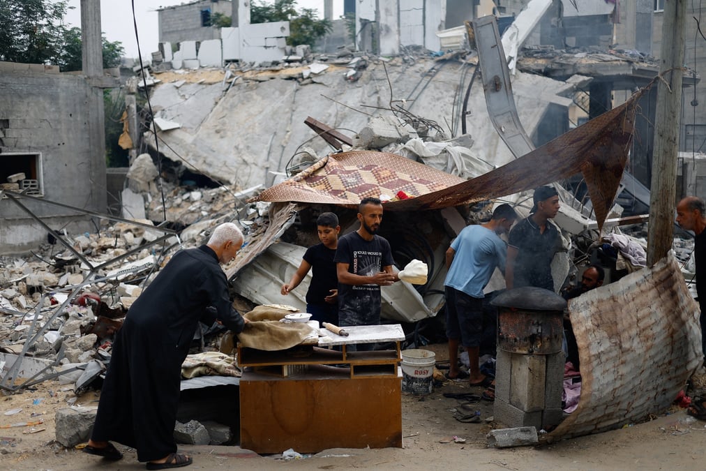 Des palestiniens preparent de la nourriture a cote des debris causes par des frappes israeliennes dans le sud de gaza