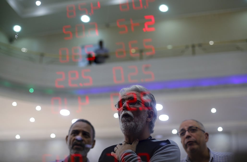 Des hommes reagissent en lisant un tableau affichant les taux de change du real bresilien par rapport au dollar americain et a plusieurs devises etrangeres a rio de janeiro