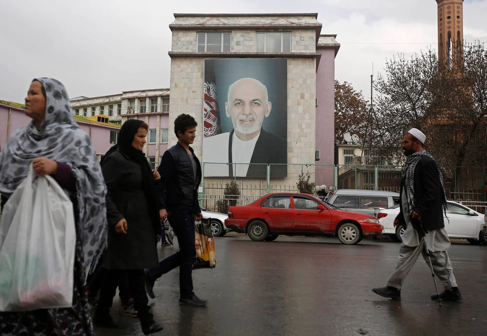 People walk past a picture of afghan president ashraf ghani on a street in kabul
