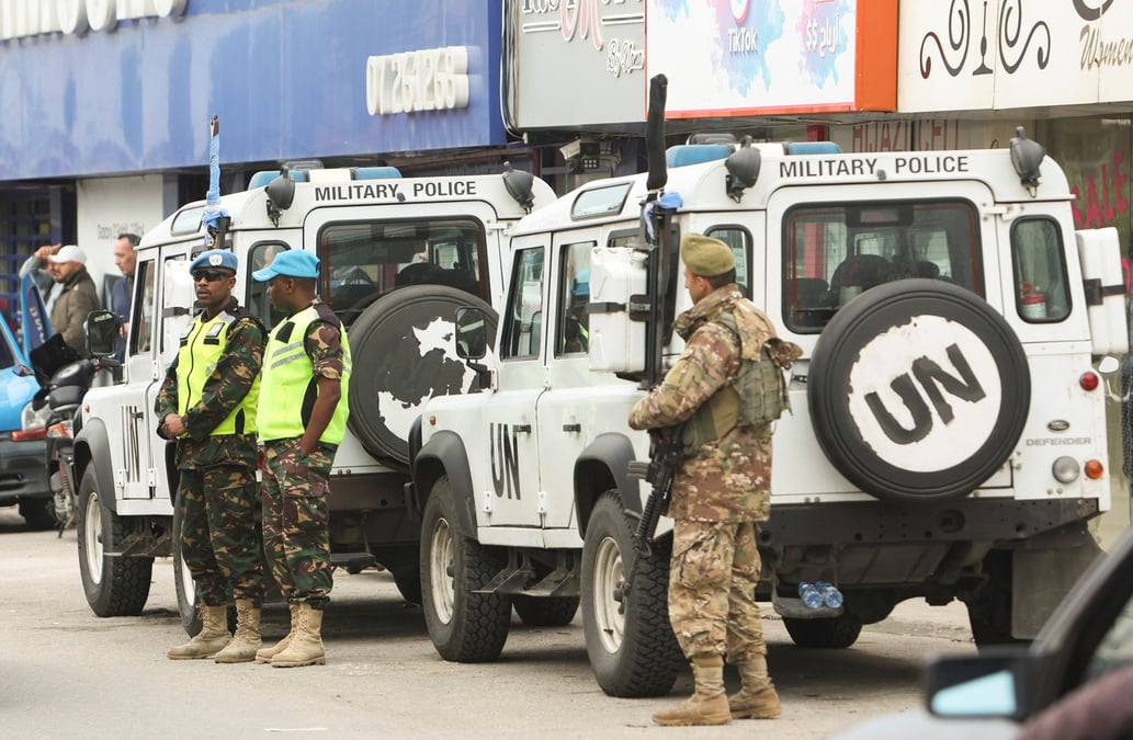 Un membre de l'armee libanaise et des casques bleu se tiennent a cote d'un vehicule de la finul a al-aqbieh