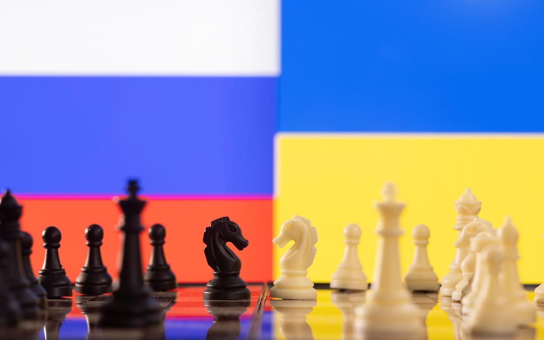 Des pieces de jeu d'echec devant les drapeaux de la russie et de l'ukraine