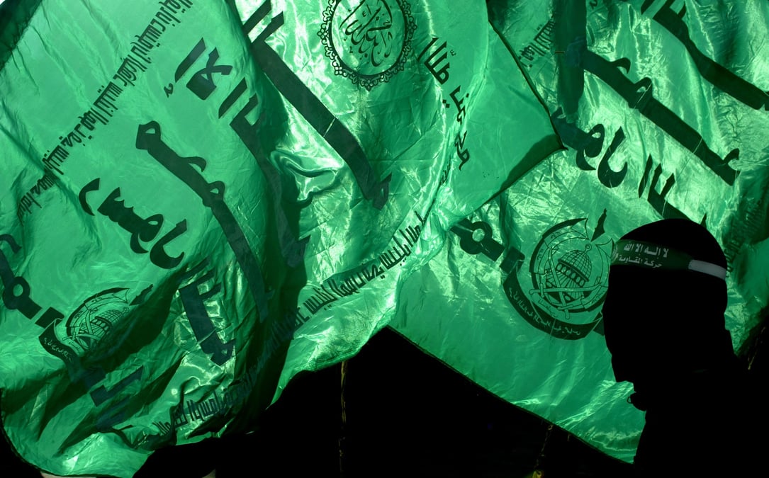 Un membre du hamas devant des drapeaux du groupe a gaza