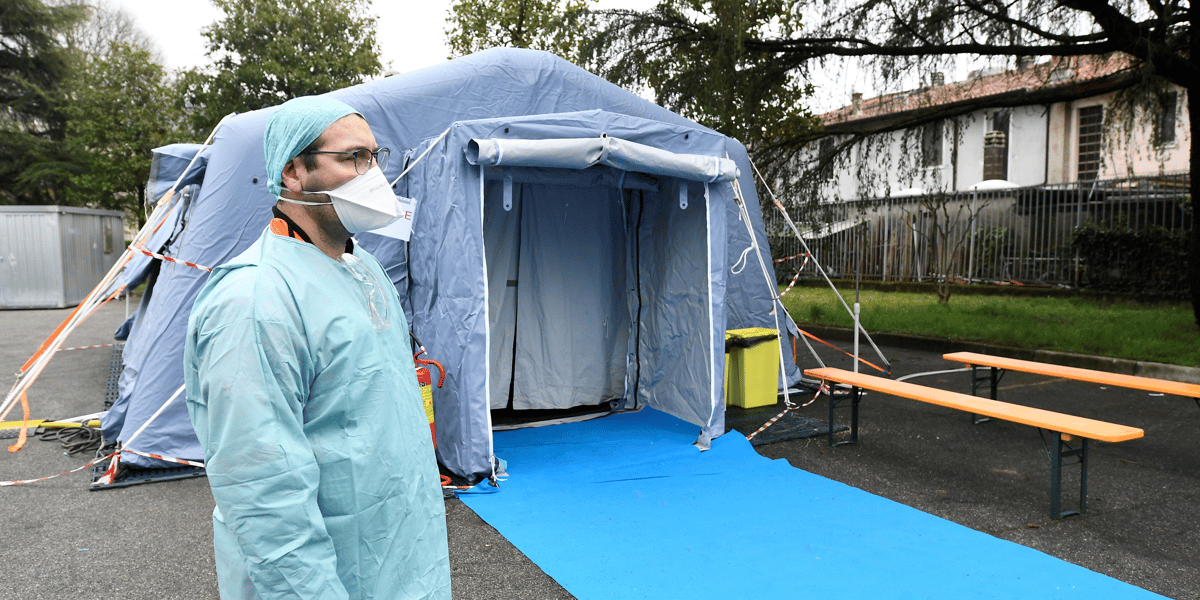 Coronavirus/Covid-19 : Un soignant portant un masque attend devant un checkpoint médical en Italie