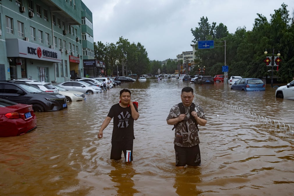 Des gens marchent dans une rue inondee a pekin
