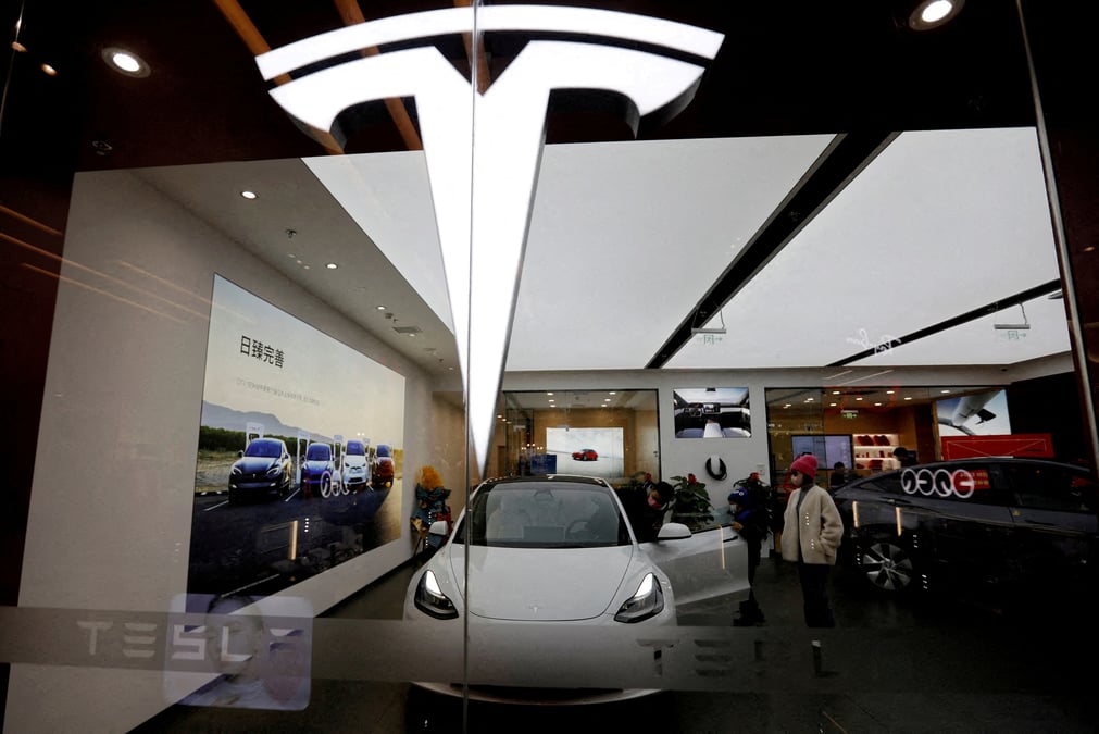 Des visiteurs observent une voiture tesla model 3 a cote d'une model y