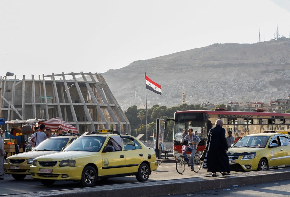 Le drapeau national syrien flotte pres des voitures de taxi a damas