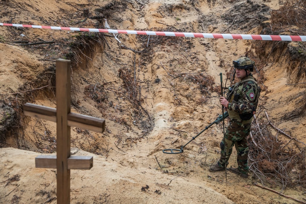 Un militaire ukrainien inspecte un charnier sur le site d'un cimetiere improvise de civils et de soldats ukrainiens dans la ville d'izioum