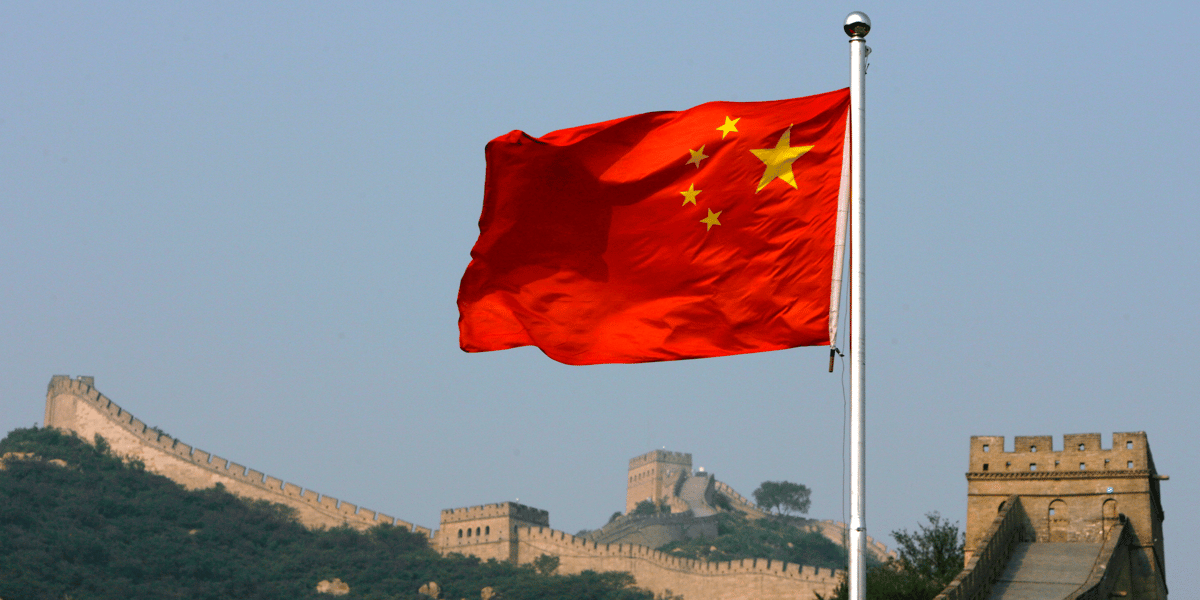 Un drapeau chinois flotte devant la grande muraille de chine, situee au nord de pekin