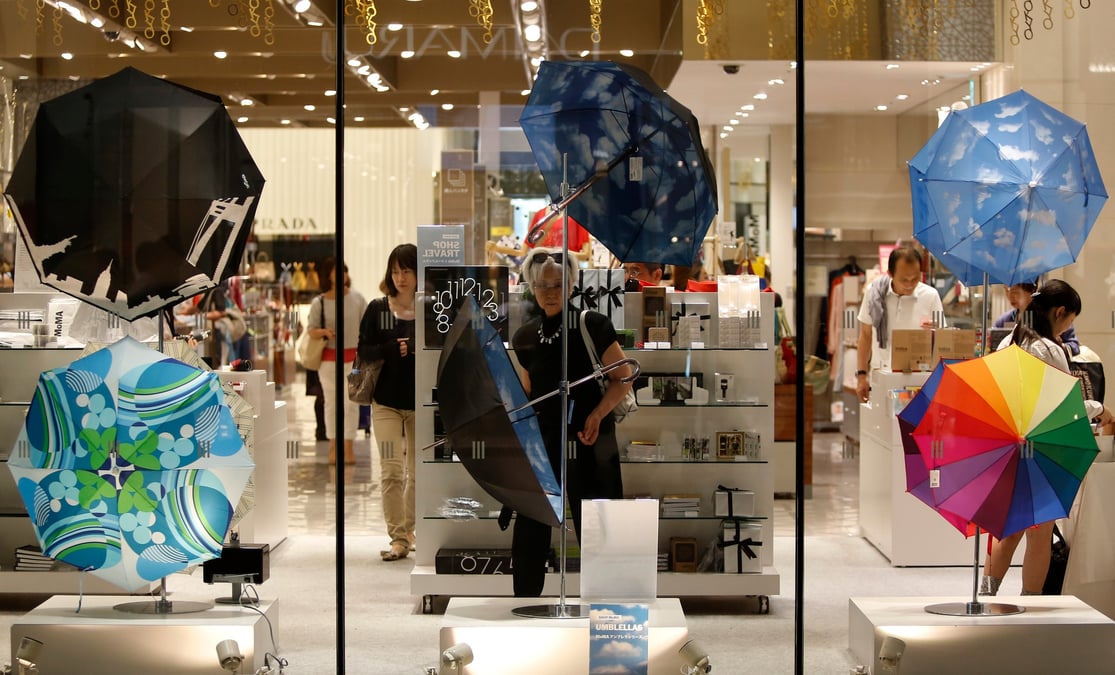 Une femme regarde des parapluies exposes dans un grand magasin de luxe a tokyo