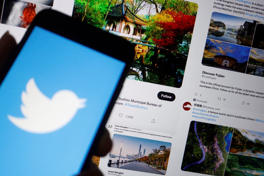 Photo d'illustration du logo de twitter affiche sur un telephone portable pres d'un ecran d'ordinateur