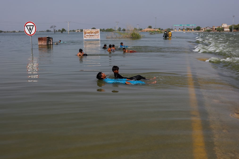 Des garcons jouent dans les eaux de crue sur l'autoroute principale de l'indus, suite aux inondations a sehwan, au pakistan