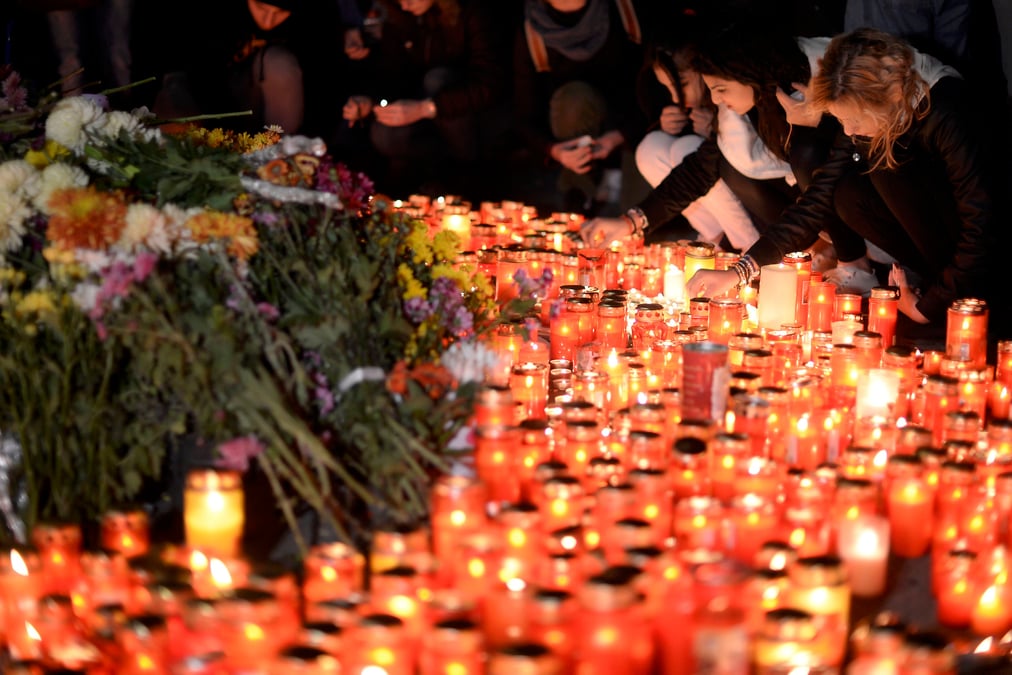 People light candles outside a nightclub, where a fire broke out on friday, in bucharest