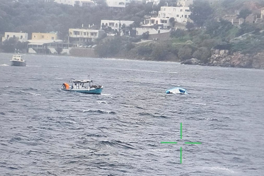 Un bateau de peche s'approche d'un bateau pneumatique a moitie coule qui transportait des migrants au large de l'ile de leros