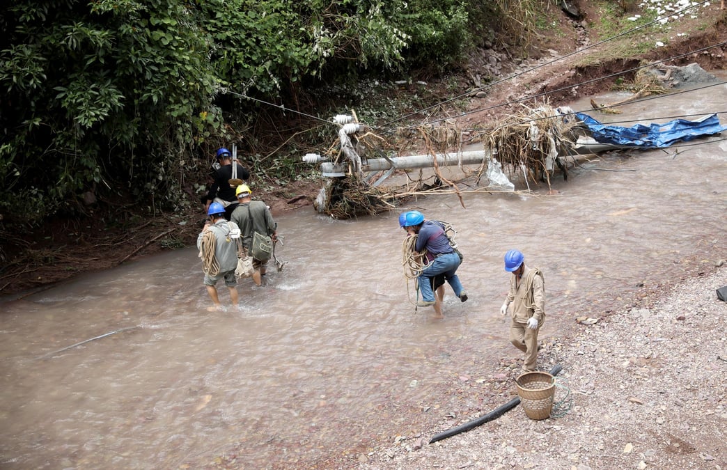 Des electriciens pataugent dans les eaux a proximite d'un poteau electrique endommage par de fortes pluies dans le comte de guzhang