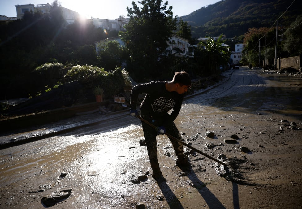 Une personne nettoie une rue couverte de boue, suite a un glissement de terrain sur l'ile italienne d'ischia