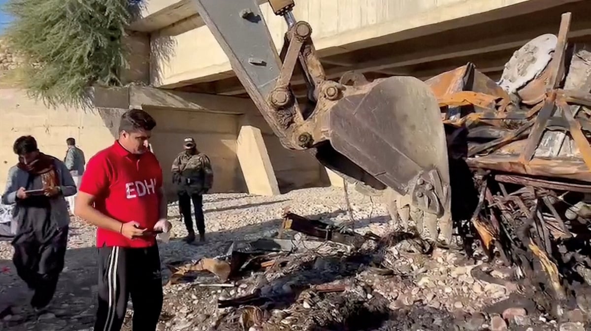 Des personnes travaillent sur le site d'un accident de bus dans le district de lasbela