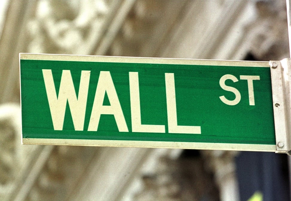 A wall street sign in front of stock exchange in new york.