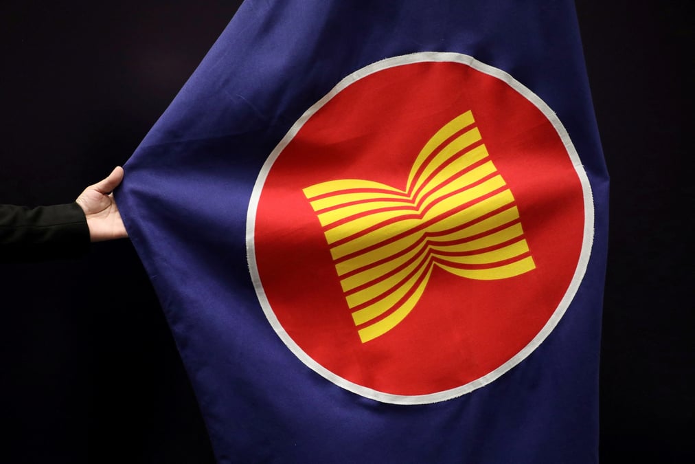 Un ouvrier ajuste un drapeau de l'asean dans une salle de reunion a kuala lumpur, malaisie