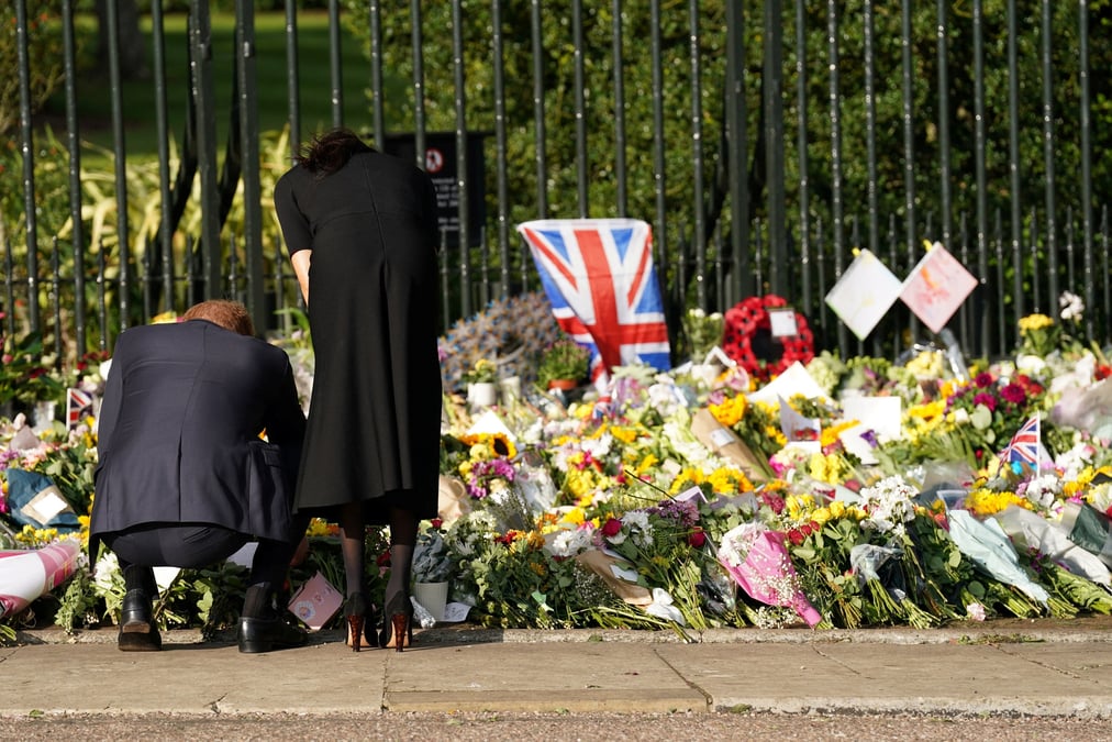 Le prince harry et son epouse meghan regardent des fleurs deposees en hommage a la reine elizabeth ii