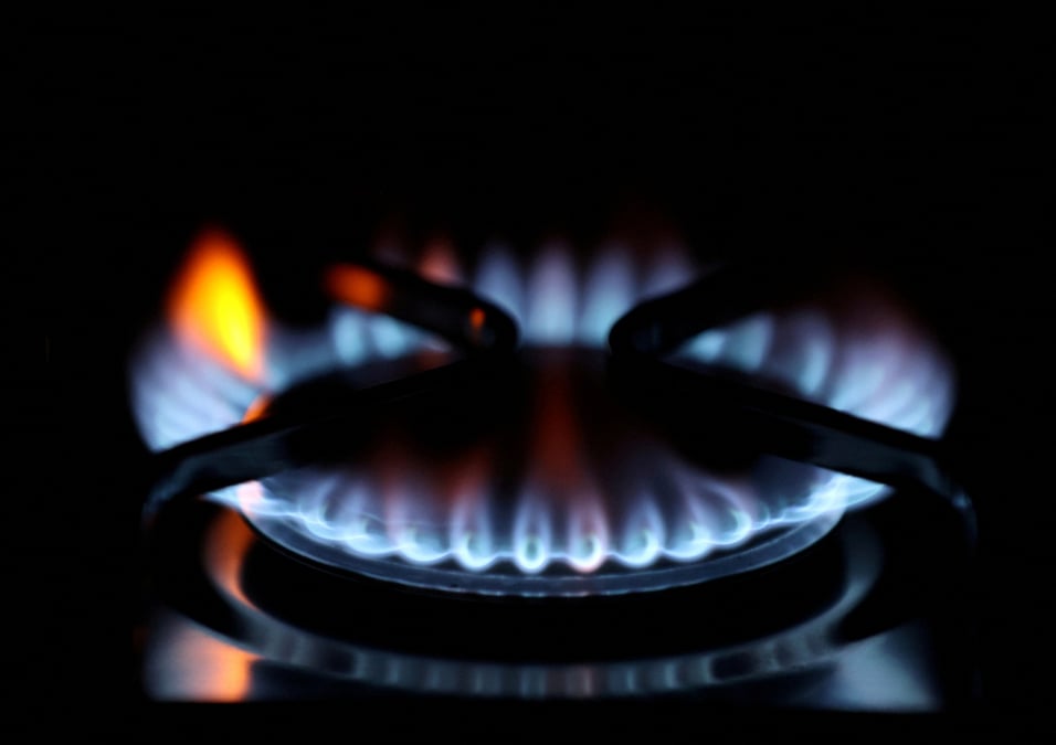 Les flammes d'un bruleur se refletent sur une plaque de cuisson
