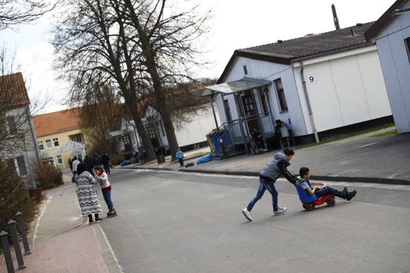 Children play outside at camp for migrants and refugees in friedland