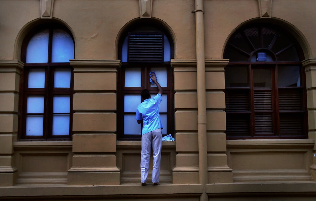 Un homme / agent d'entretien nettoie la vitrine d'un magasin à Colombo (Sri Lanka)