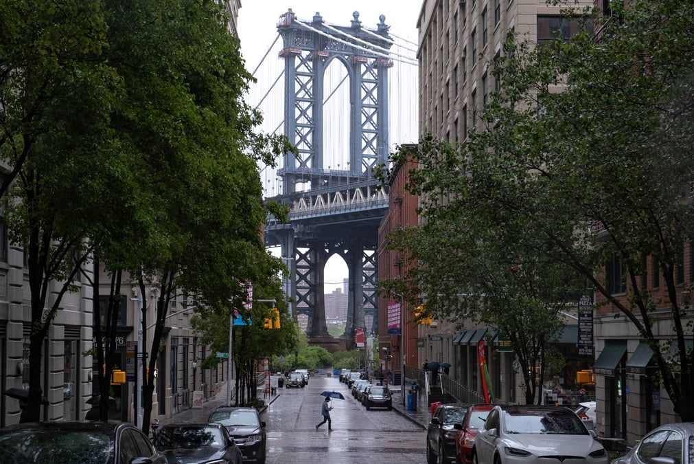 Un pieton passe sur washington street dans le quartier de dumbo a brooklyn, avec le pont de manhattan en arriere-plan, a new york