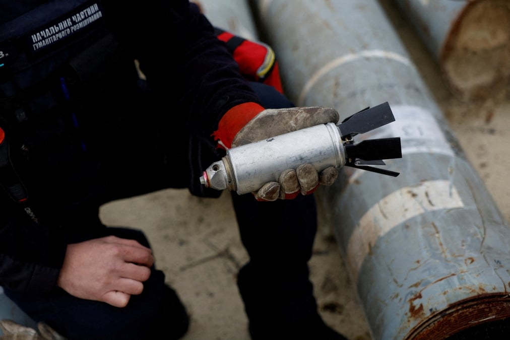 Un soldat ukrainien tient une bombe a sous-munition desamorcee