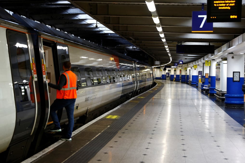 Un employe ferroviaire a cote d'un train a la gare d'euston a londres, en grande-bretagne