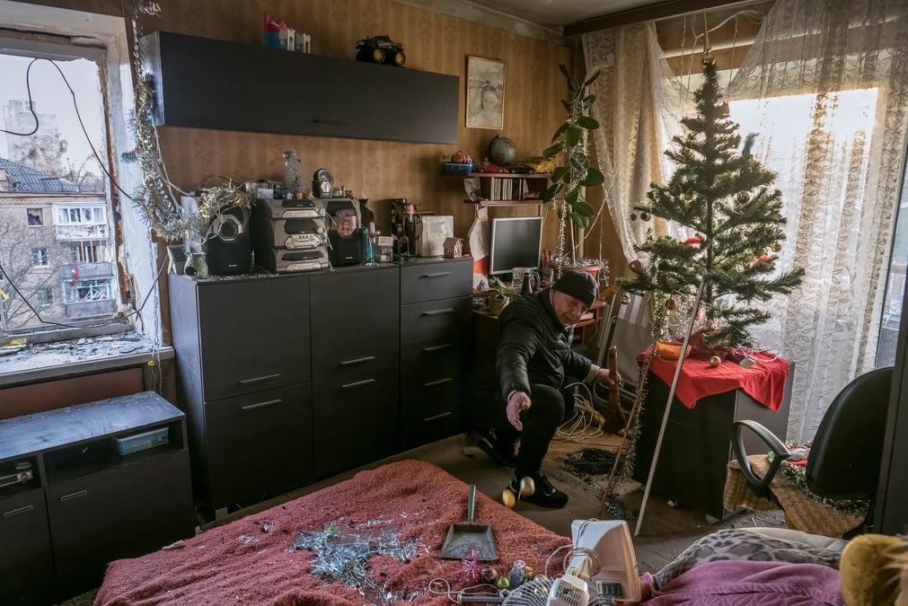 Un habitant enleve les morceaux de verre des fenetres brisees de son appartement, dans un immeuble residentiel endommage par un tir de missile russe, a kyiv