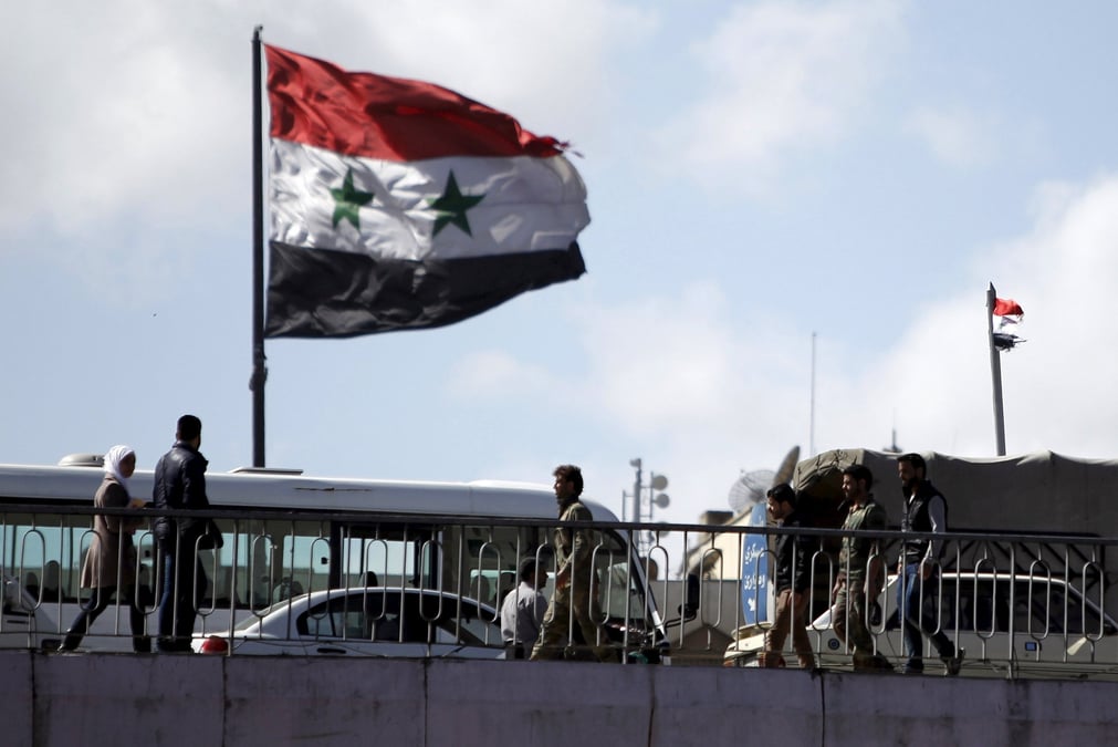 Des personnes marchent pres d'un drapeau syrien sur le pont du president a damas
