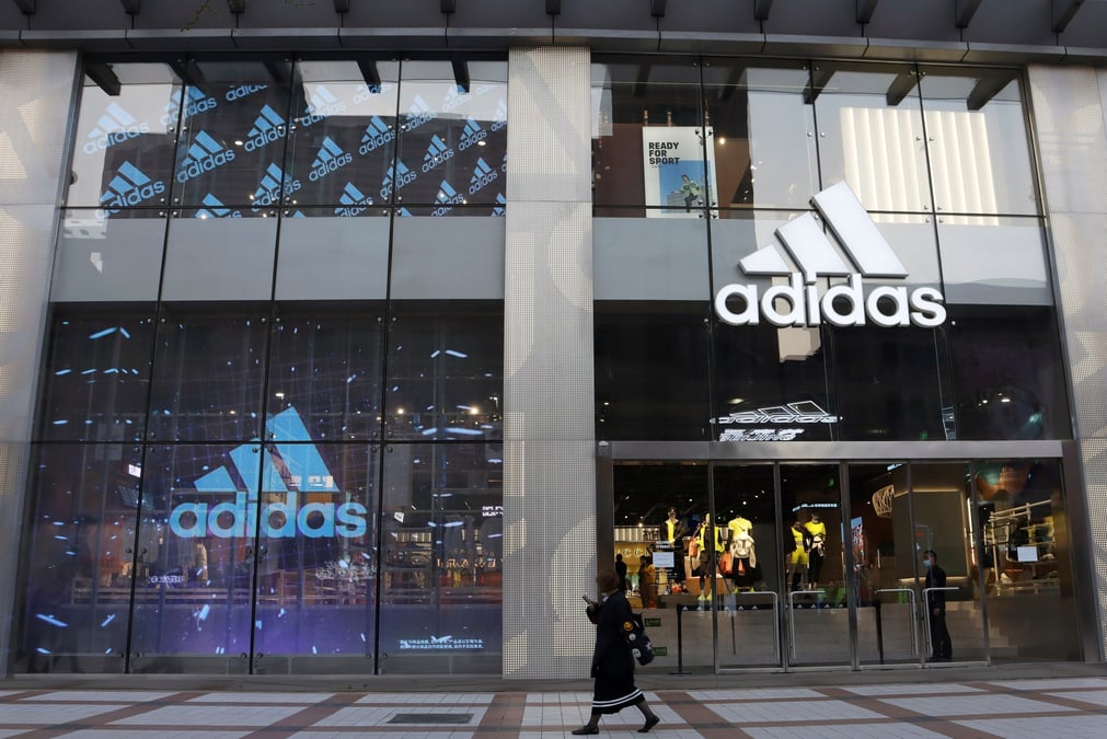 Une femme passe devant un magasin d'adidas dans un centre commercial de pekin