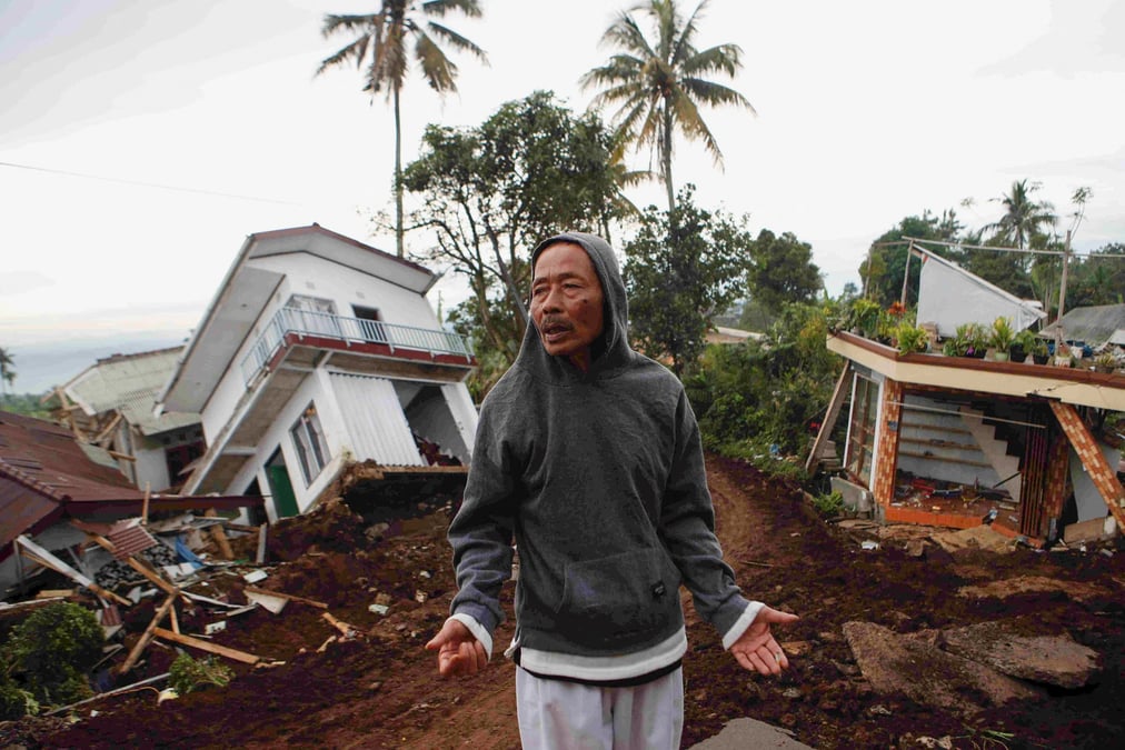 Un homme pres de maisons gravement endommagees apres le tremblement de terre de lundi a cianjur, en indonesie