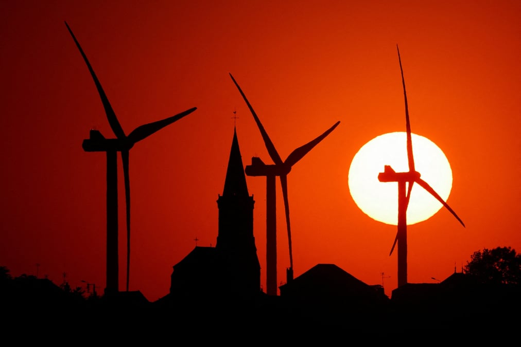Photo d'archives d'eoliennes et d'une eglise au coucher du soleil a bethencourt