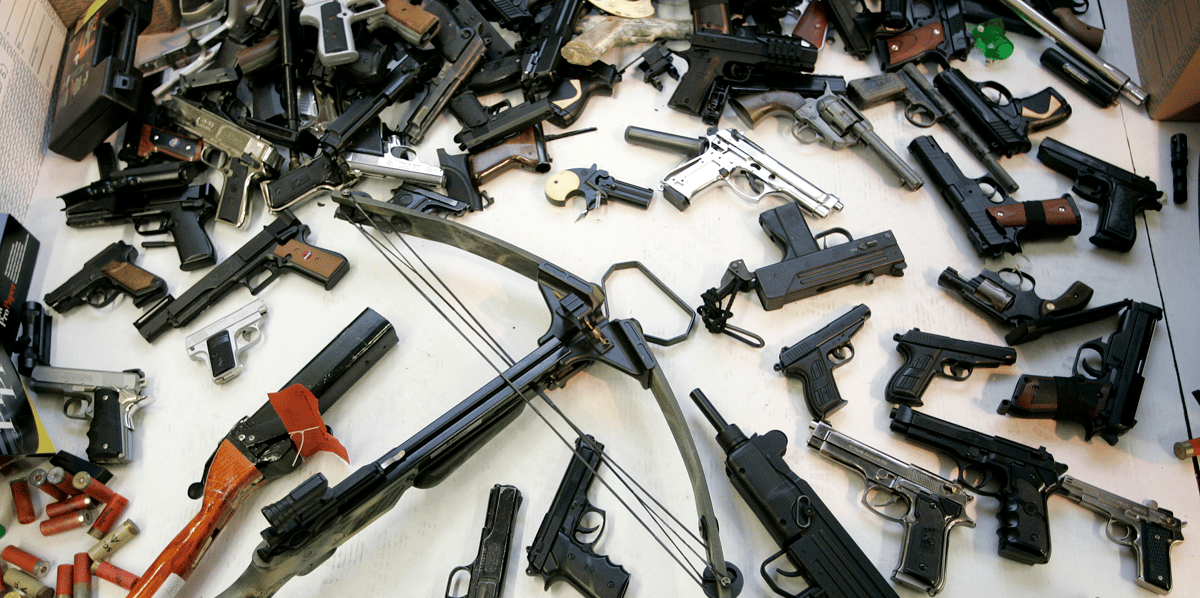 Un arsenal d'armes à feu (pistolets, munitions, fusils) posé sur une table à Manchester