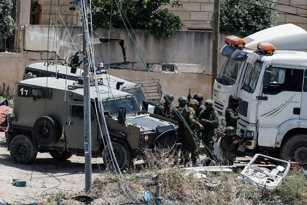 De nombreux soldats israeliens arretent un homme palestinien lors d'un raid en cisjordanie occupee