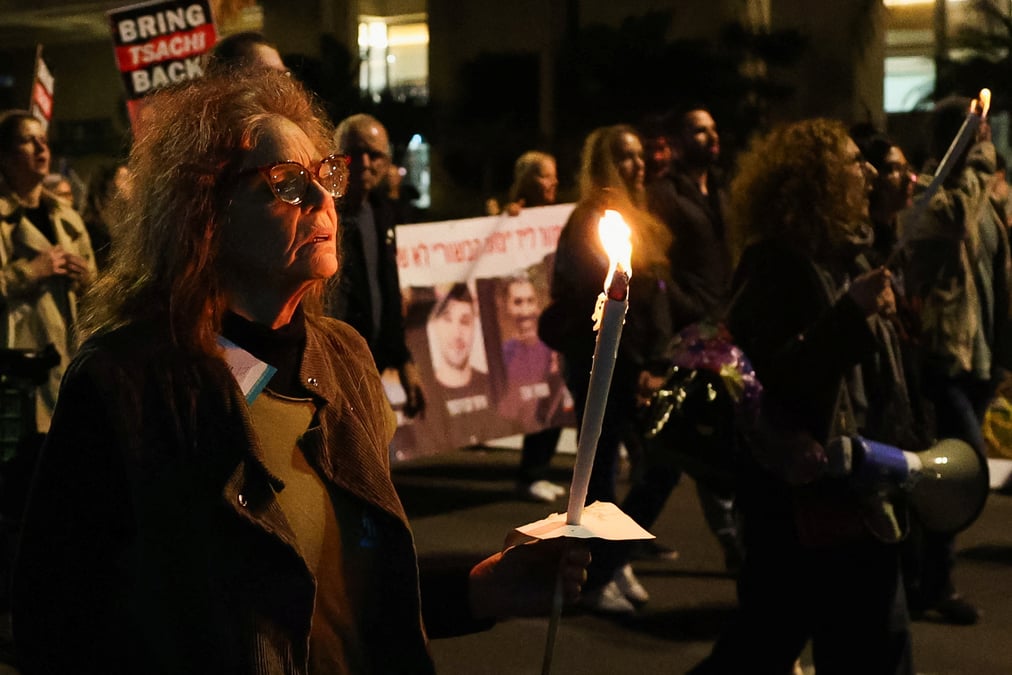 Photo d'une femme qui tient une bougie alors que les gens protestent apres que l'armee israelienne a annonce qu'elle avait tue par erreur trois otages israeliens detenus a gaza