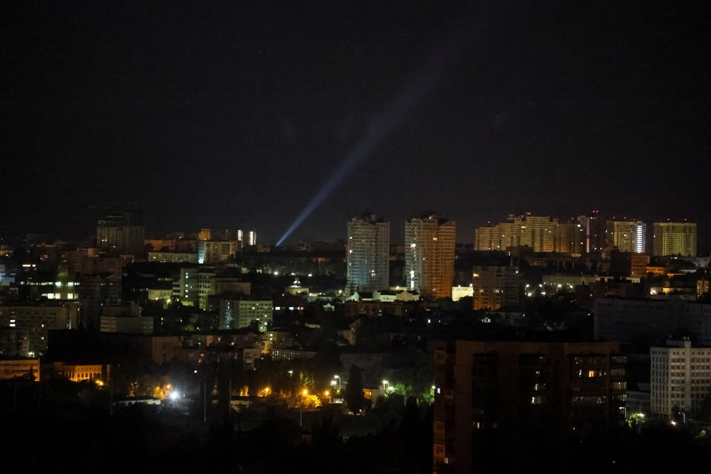 Des militaires ukrainiens utilisent un projecteur alors qu'ils recherchent des drones dans le ciel au-dessus de la ville lors d'une attaque russe