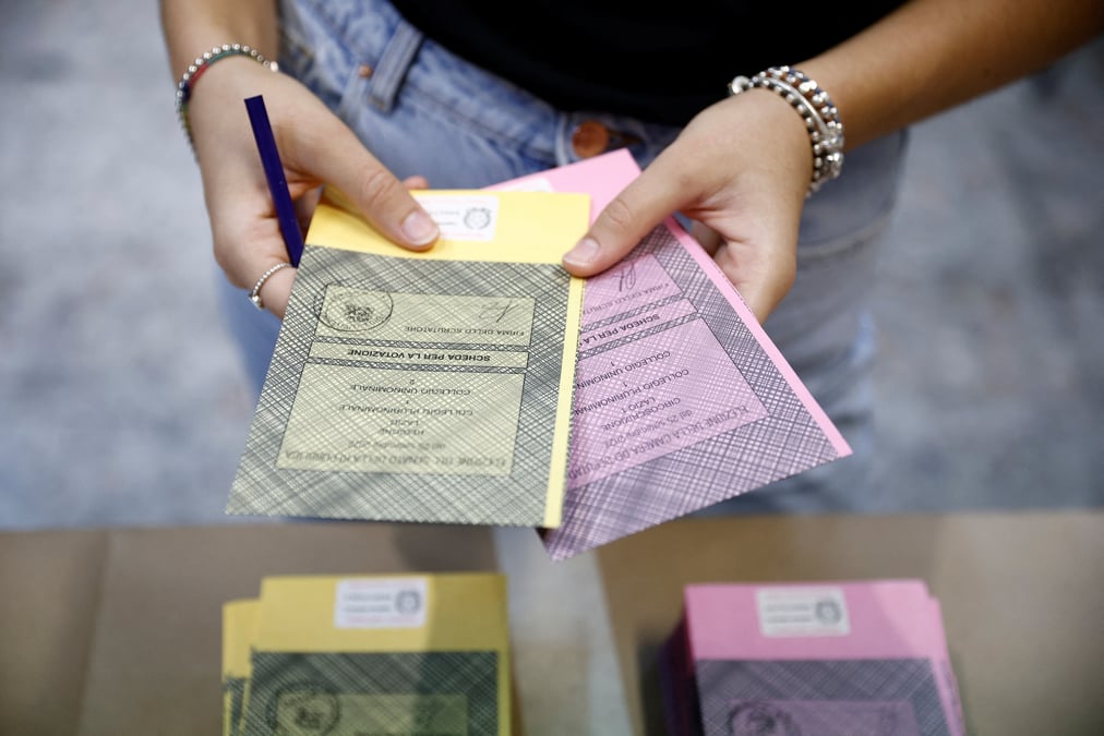 Une personne tient des bulletins de vote dans un bureau de vote