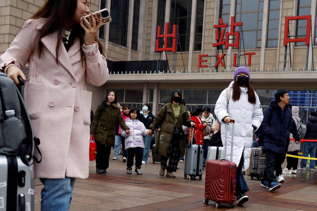 Des voyageurs marchent avec leurs bagages a l'exterieur de la gare de pekin pendant la fete du printemps