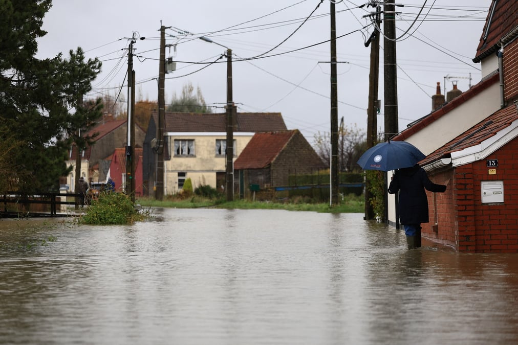 Une femme marche dans une rue inondee du doulac, dans le nord de la france