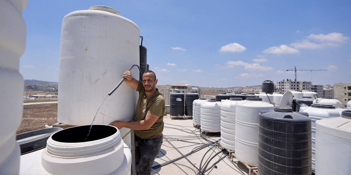 Un habitant de Kufr Aqab au milieu des réservoirs d’eau d’un immeuble, le 29 juillet.