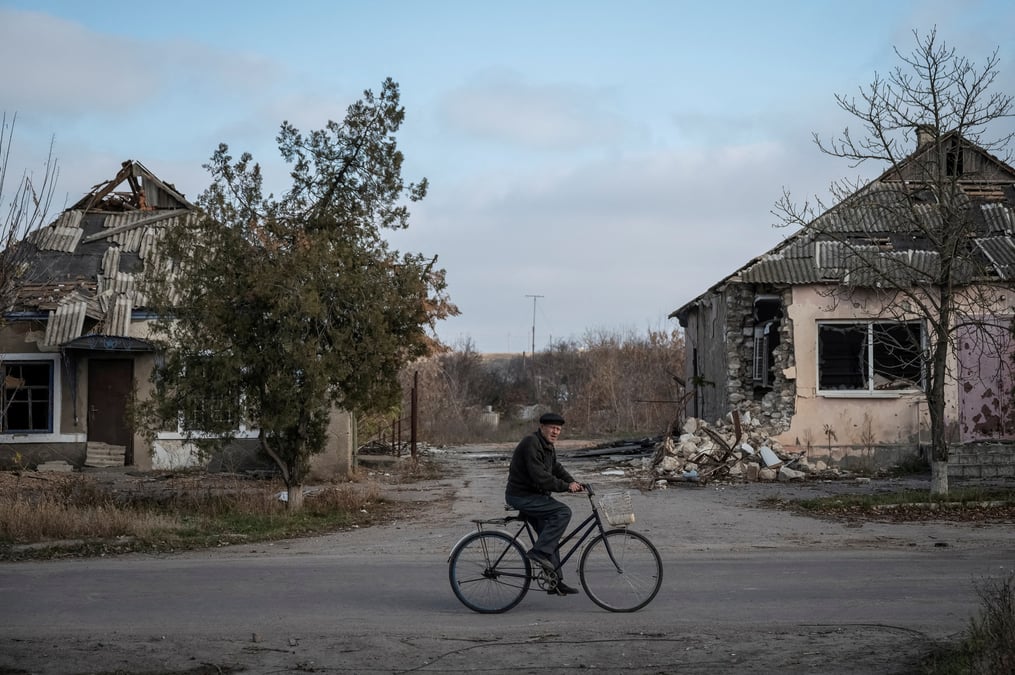 Un habitant fait du velo pres de maisons detruites dans le village d'arkhanhelske, dans la region de kherson