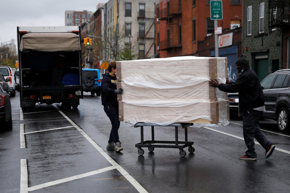 Des employés déplacent une pile de nouveaux cercueils d'un entrepôt vers un camion de livraison, le 24 avril 2020, dans le quartier de Brooklyn, à New York, extrêmement touchée par la pandémie de coronavirus (COVID-19).
