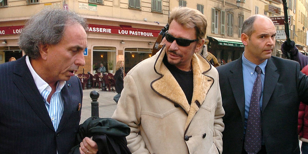 Johnny Hallyday, entouré de son avocat Maître Gilles-Jean Portejoie (à gauche) et d’un garde du corps, arrive au palais de justice de Nice, pour sa confrontation avec Marie-Christine Vo, le 12 mars 2004.