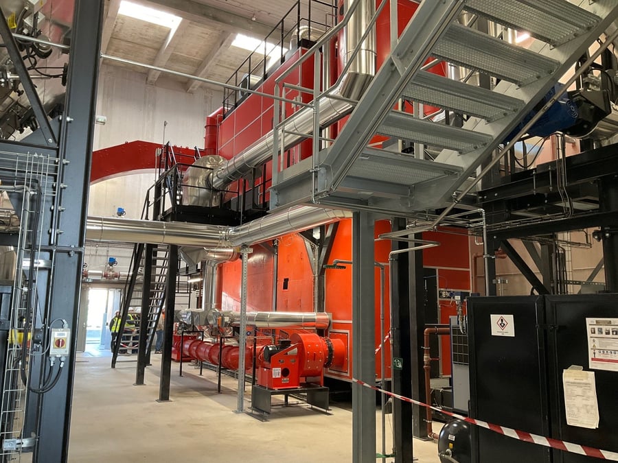 Fonctionnant comme une chaudière domestique, une chaudière à bois brûle la biomasse pour faire chauffer de l'eau à 100 degrés celcius. L'eau chaude est ensuite transportée vers les radiateurs via un réseau souterrain de canalisations.