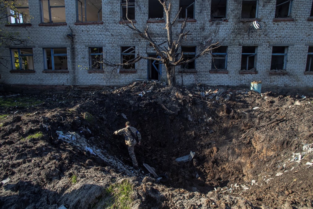 Un soldat ukrainien sort d'un cratere d'obus devant un batiment pres de la ville de lyman