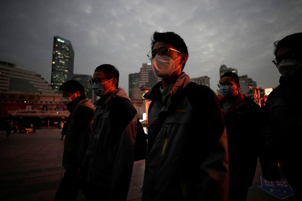 Des personnes portant des masques de protection marchent devant la gare de shanghai
